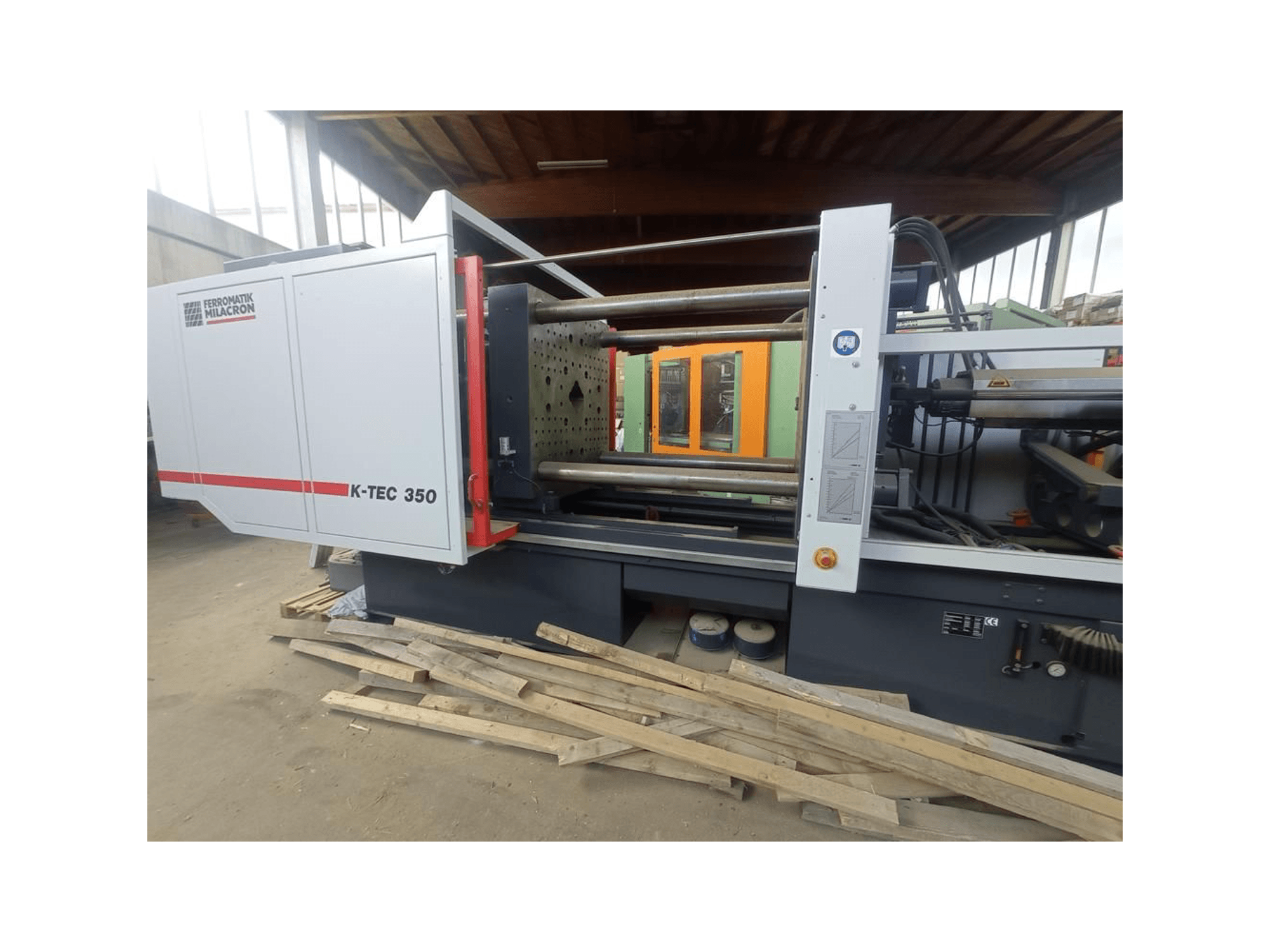 K-TEC 350 da Ferromatik Milacron, visto de lado, mostrando a sua complexa maquinaria e controlos operacionais.