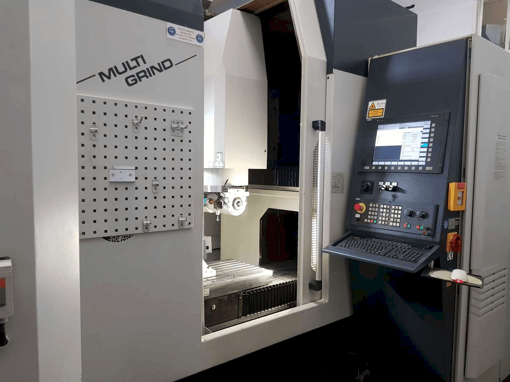 Máquina CNC Multi Grind com vista frontal, com um painel de controlo, painel de armazenamento e uma área de trabalho aberta.